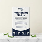 Smile Dew peroxide-free teeth whitening strips box on marble with fresh mint leaves, 14 day treatment
